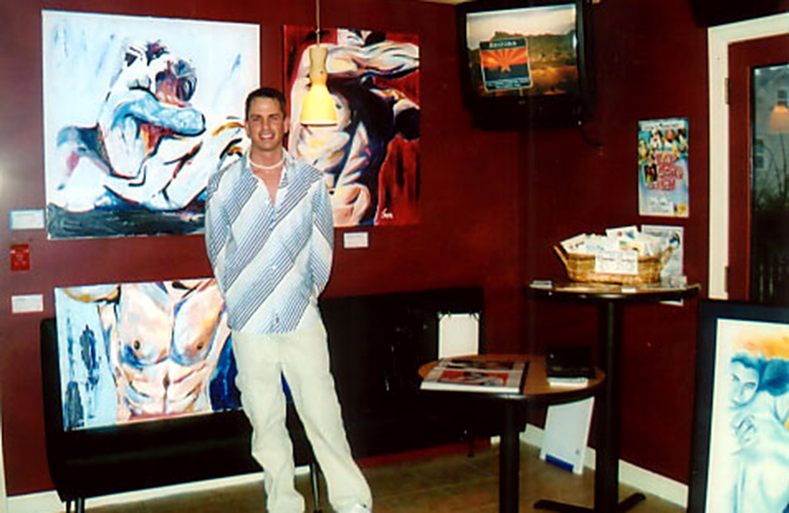 Brenden Sanborn at his first solo show in 2003, standing in front of his large expressive figure paintings on a red wall
