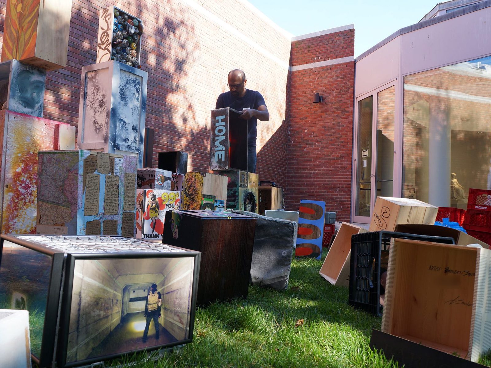 An installation artist assembling Box City, Rahul Mitra's collaborative installation of painted boxes, at Piece Work, the 2013 Portland Museum of Art Biennial, with Brenden Sanborn's signed box at lower right