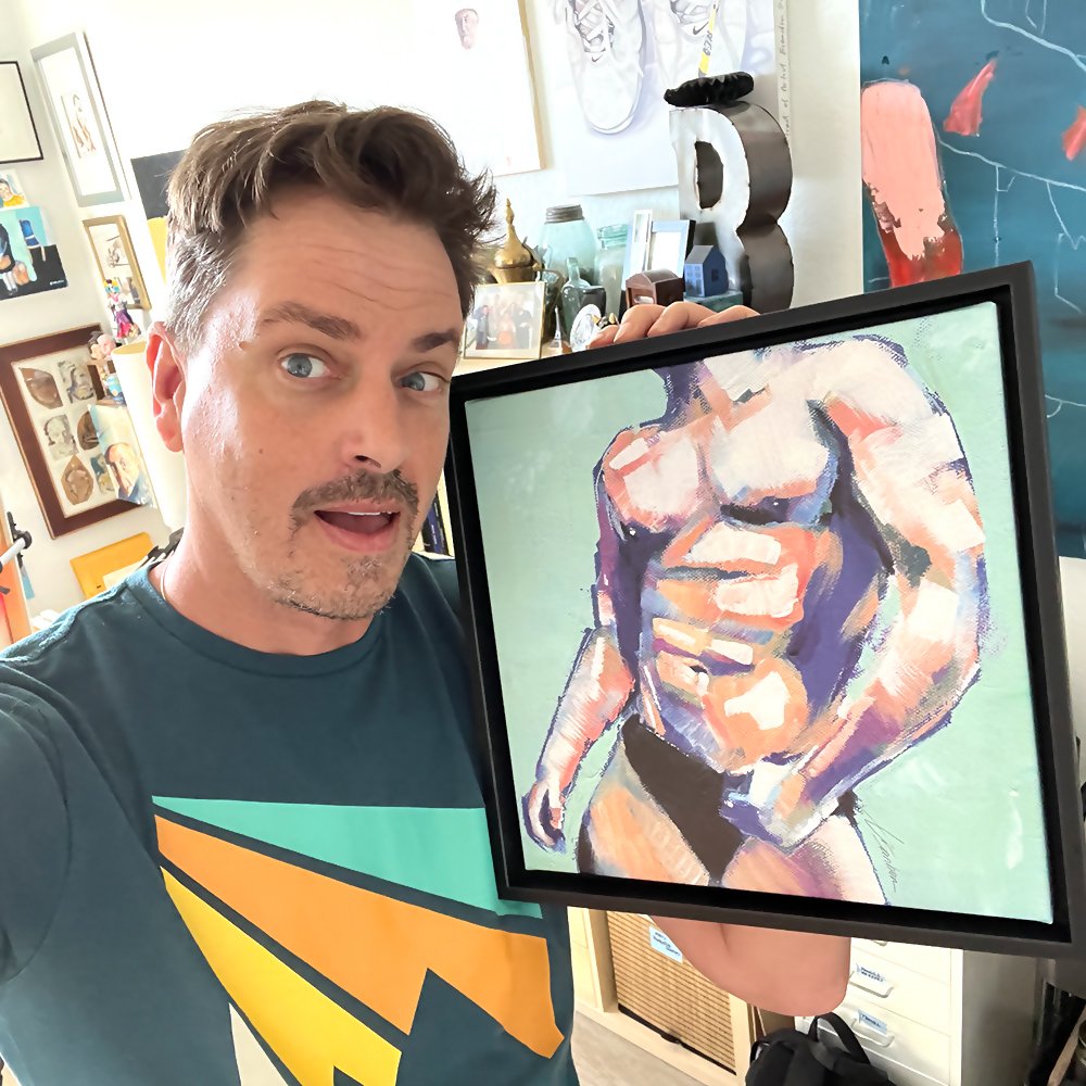 Brenden Sanborn holding a framed painting of a male figure in purple, peach and mint green