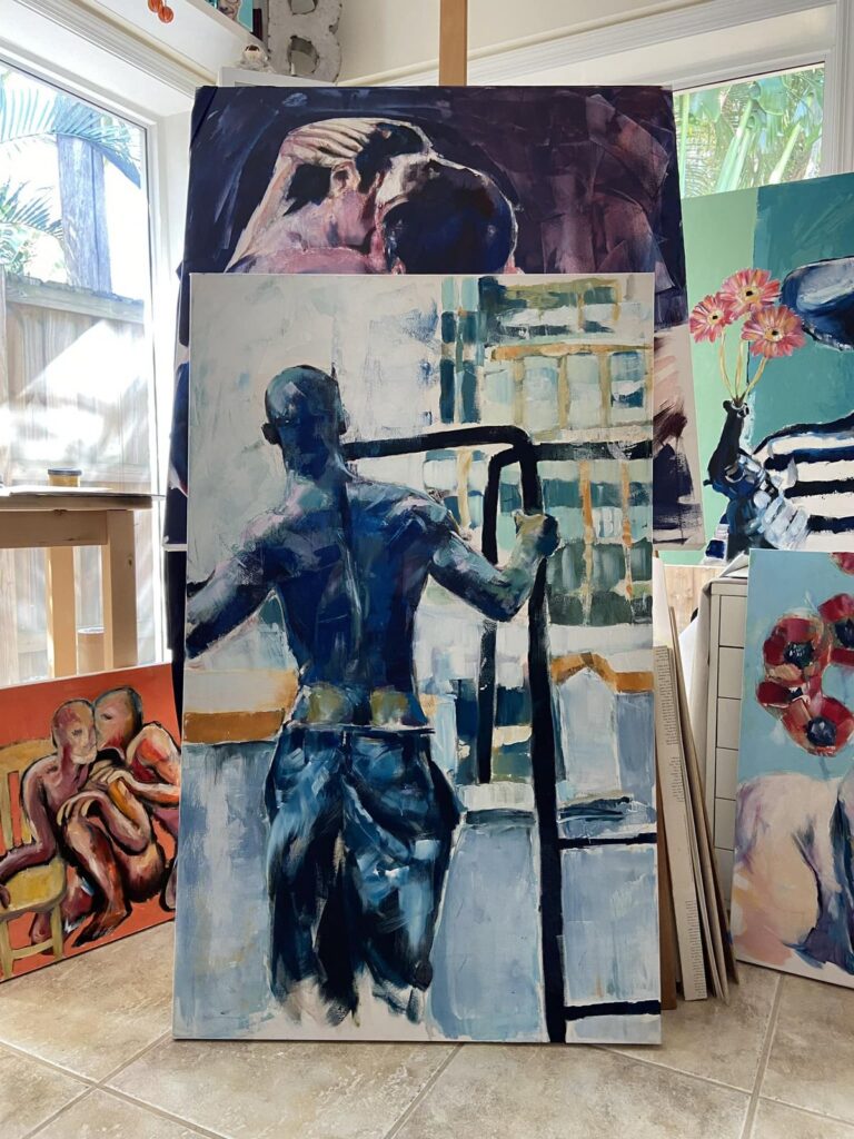Large paintings by Brenden Sanborn stacked against the wall of his sunny studio