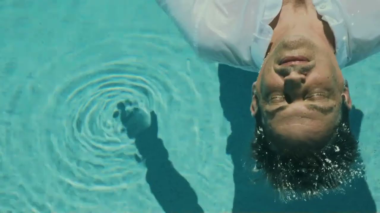 Brenden Sanborn floating in a pool in a white shirt, a still from the short film Unspoken by Matteo Trisolini